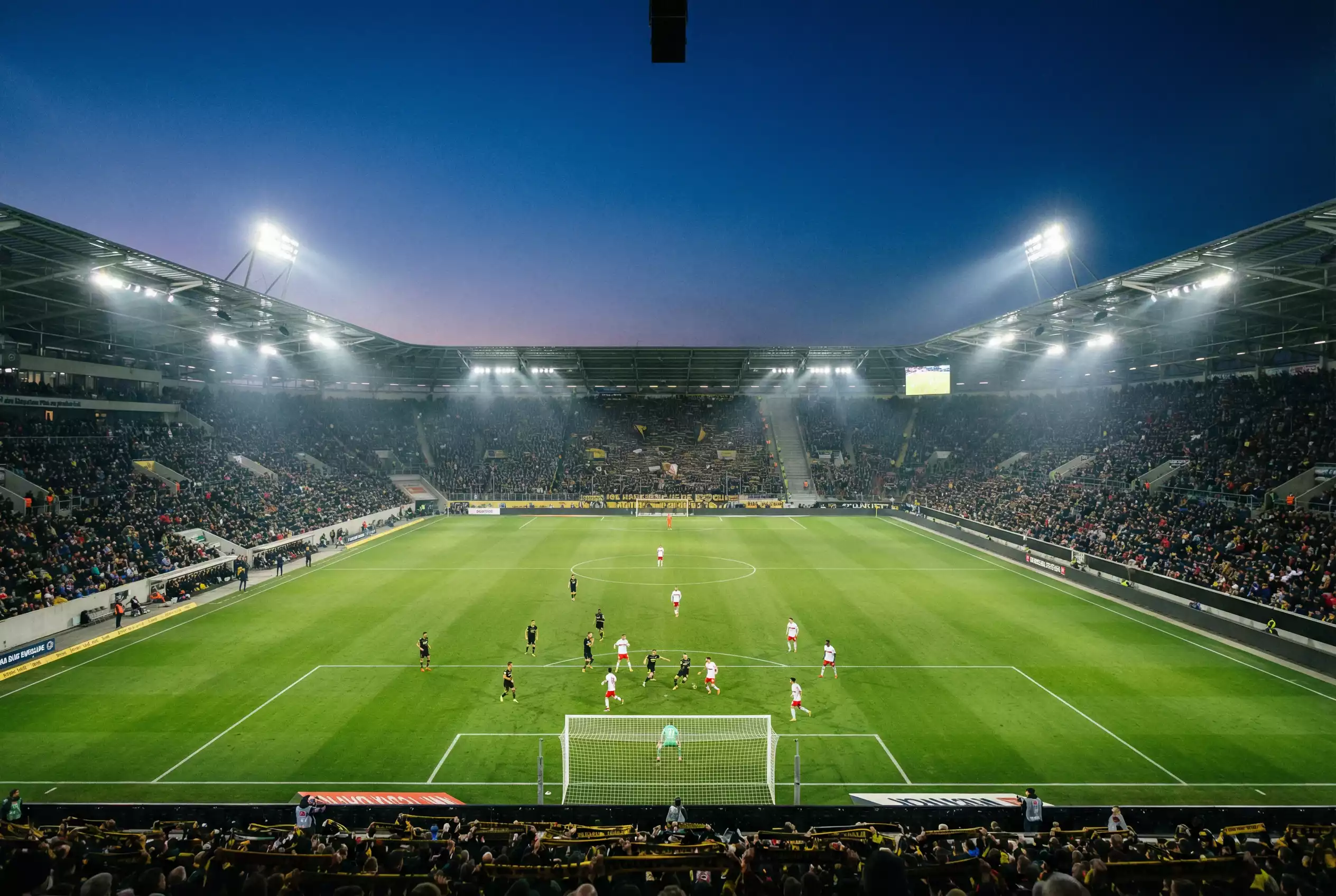 Panoramica dello stadio di calcio della Bundesliga con tabellone luminoso durante una partita serale